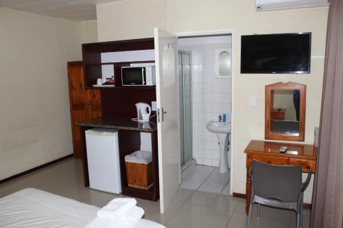 a room with a bed and a desk with a microwave at Purple Olive Guest House in Pretoria