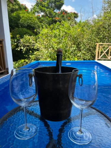 a bottle of wine in a bucket on a table with two glasses at Villa unter Palmen in Jarabacoa