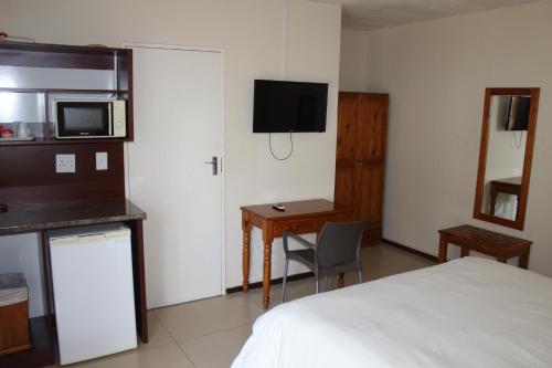 a bedroom with a bed and a desk and a microwave at Purple Olive Guest House in Pretoria