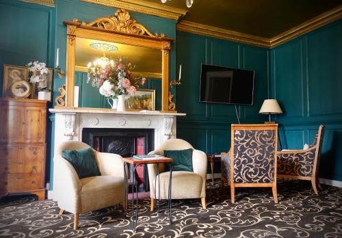 a room with a fireplace and two chairs and a mirror at Cley Hall in Spalding