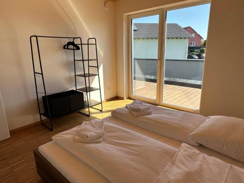 2 Betten in einem Zimmer mit einem großen Fenster in der Unterkunft EBM-Apartments Altenmünster mit Wallbox in Altenmünster
