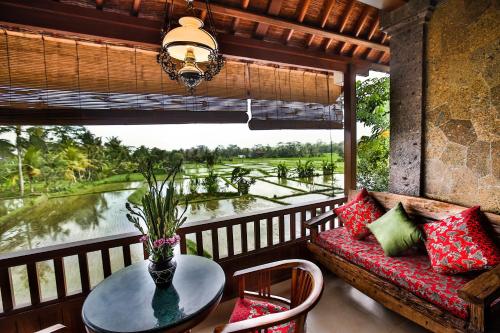 a balcony with a table and a couch and a window at Bliss Ubud Spa Resort in Ubud