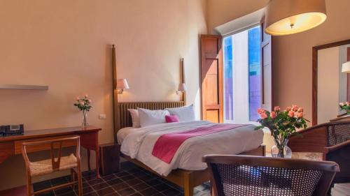 a hotel room with a bed and a desk at Rosas & Xocolate Boutique Hotel and Spa Merida, a Member of Design Hotels in Mérida