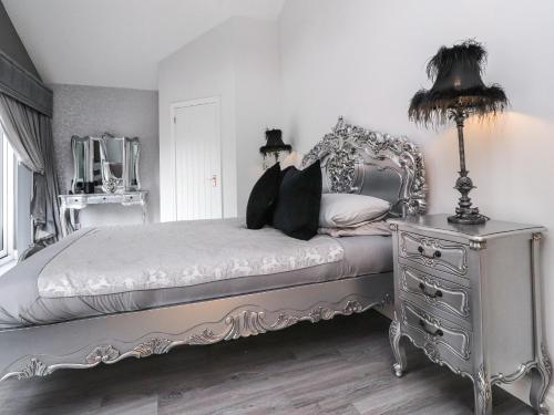 a bedroom with a bed and a dresser and a lamp at Damson Cottage in Poulton le Fylde