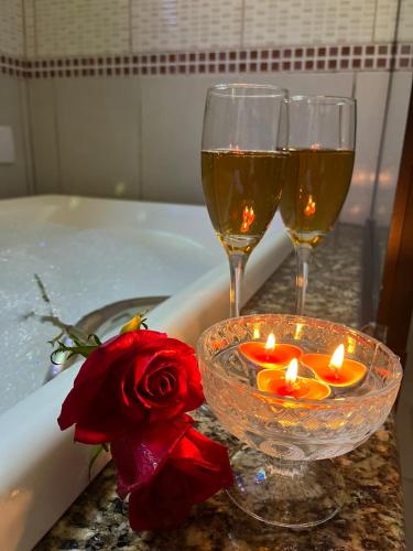 ペネドにあるPousada do Solのバスタブの上にワイングラス2杯とバラの花とキャンドル