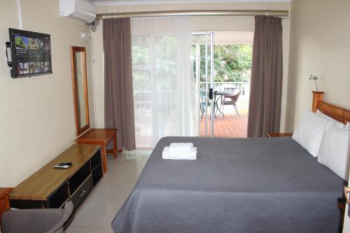 a hotel room with a bed and a balcony at Purple Olive Guest House in Pretoria