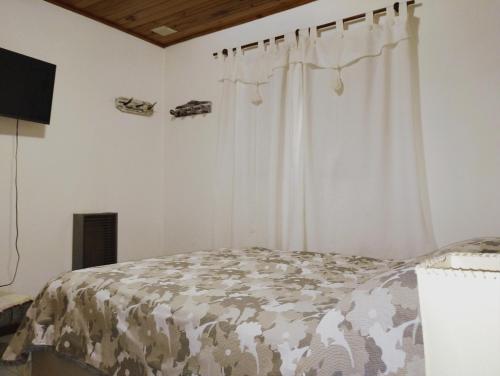 1 dormitorio con cama con edredón y cortinas en Colibrí House en San Martín de los Andes