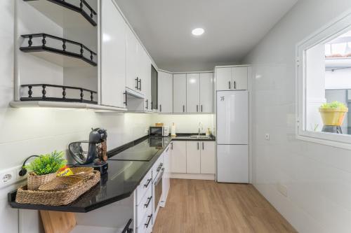 a kitchen with white cabinets and black countertops at Casa Augusto - junto al Teatro Romano, con garaje in Merida
