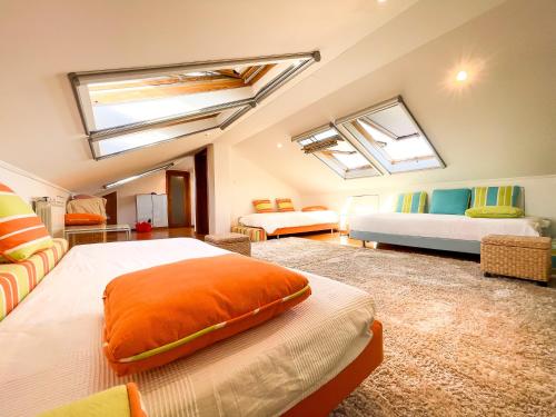 a large room with two beds and two windows at Quinta do Cutato - Beatriz Guest House - Sotão in Santo Estêvão