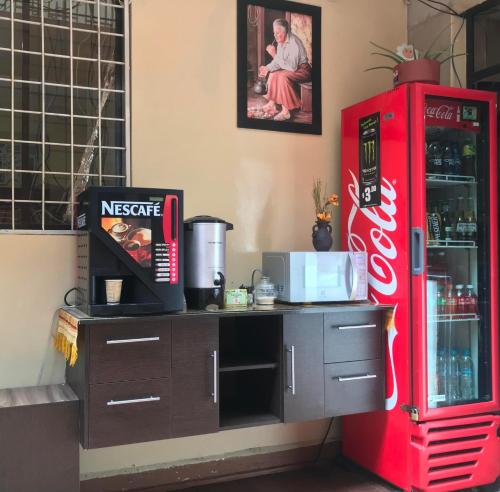 a coca cola refrigerator next to a counter with a microwave at Hotel Norte in Cuenca