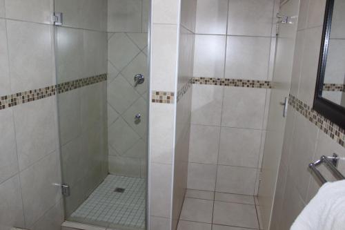 a shower with a glass door in a bathroom at Purple Olive Guest House in Pretoria