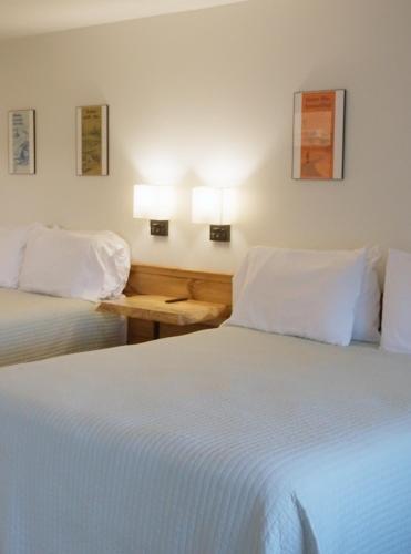 two beds in a hotel room with white sheets at Bingham Motor Inn in Bingham