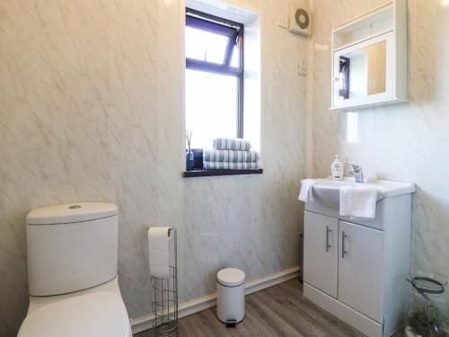 a bathroom with a toilet and a sink and a window at Hideaway in Alfreton