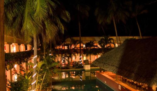 a building with a pool and palm trees at night at Villas Arqueologicas Chichen Itza in Chichén-Itzá