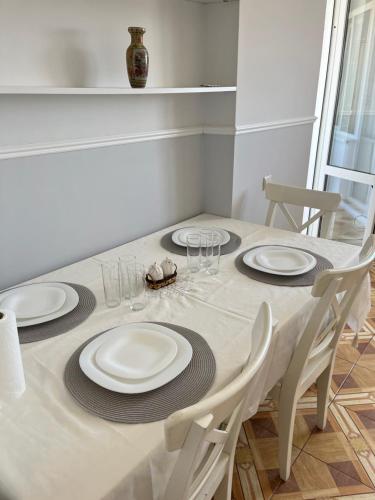 a dining room table with white plates and chairs at Flat in Chisinau in Chişinău