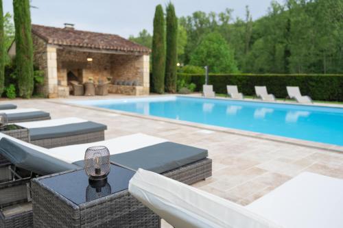 a swimming pool with chairs and a table with a wine glass at Château Forge du Roy in Mauzens-et-Miremont