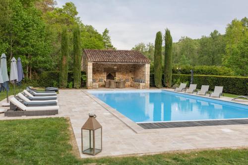 a swimming pool in a yard with chairs and a fireplace at Château Forge du Roy in Mauzens-et-Miremont
