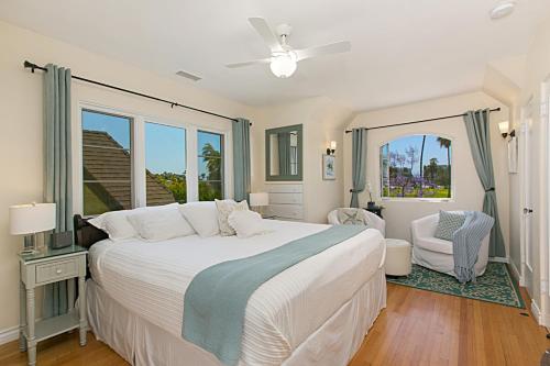 a bedroom with a large white bed and a window at Coronado Seaside Cottage in San Diego