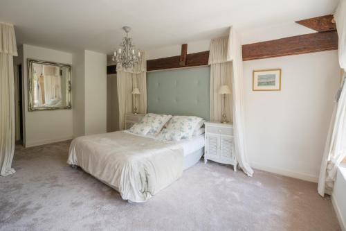 a bedroom with a white bed and a chandelier at Château Forge du Roy in Mauzens-et-Miremont