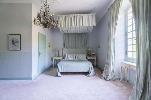 a bedroom with a bed and a chandelier at Château Forge du Roy in Mauzens-et-Miremont