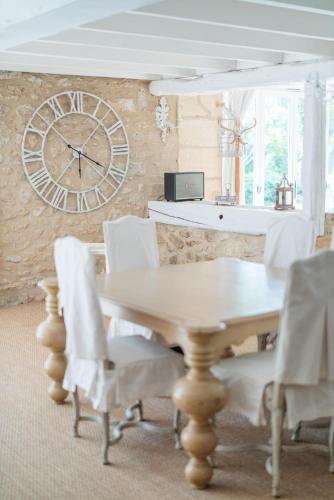 a dining room with a table and a clock on a wall at Château Forge du Roy in Mauzens-et-Miremont