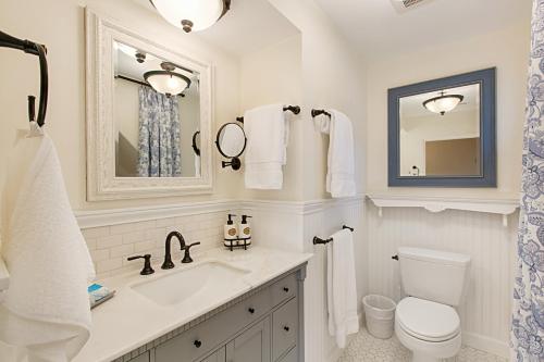 een badkamer met een wastafel, een toilet en een spiegel bij Coronado Seaside Cottage in San Diego