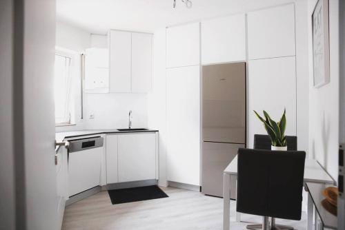 a white kitchen with a table and a black chair at Calm and Cozy apartment Bivange in Livange