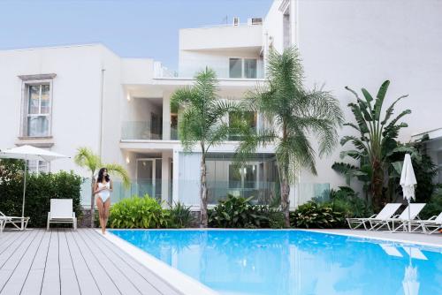een vrouw die bij een zwembad voor een gebouw staat bij Cora Luxury Home in Taormina