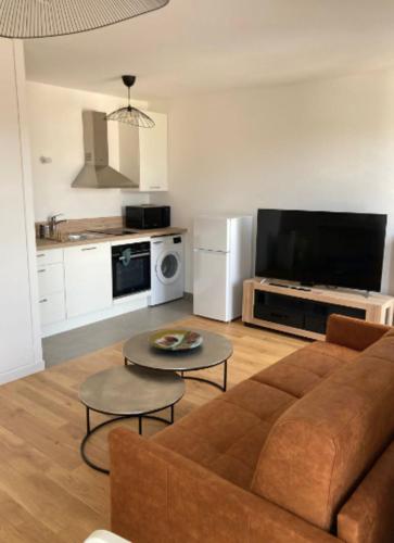 ein Wohnzimmer mit einem braunen Sofa und einer Küche in der Unterkunft Superb 45 m quiet in Suresnes