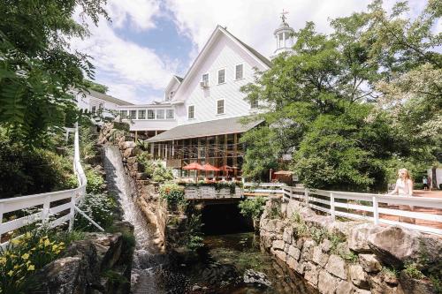 a woman standing in front of a building next to a river at Mill Falls Resort Collection at the Lake in Meredith