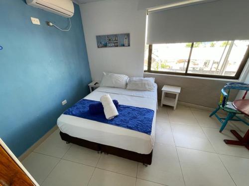 a bedroom with a bed with blue walls and a window at La Posada De Lulú in San Andrés