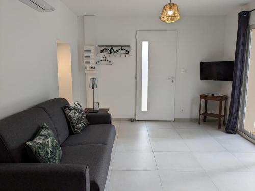a living room with a couch and a television at L'atelier: charmante annexe indépendante in Mâcon