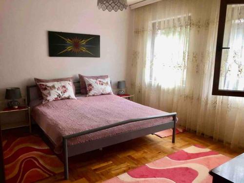 - une chambre avec un grand lit et une couverture rose dans l'établissement Cozy, peaceful apartment near city center., à Peje