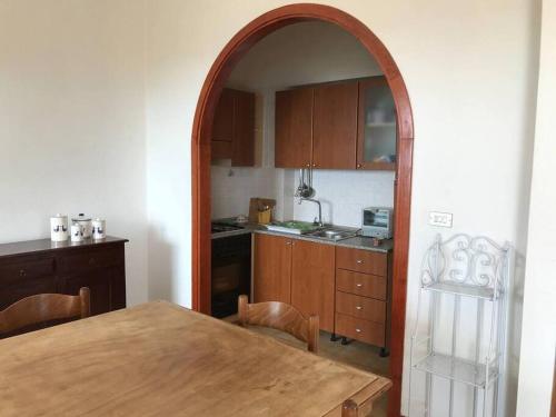 una cocina con una mesa de madera y un arco en Appartamento Ginepro, en Capitana