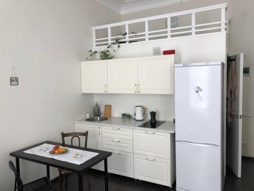 uma cozinha branca com uma mesa e um frigorífico em Makij apartment for night 4 em Narva