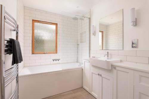 een witte badkamer met een bad en een wastafel bij Ballater Bungalow - 4 bed - Beautiful Garden in Ballater