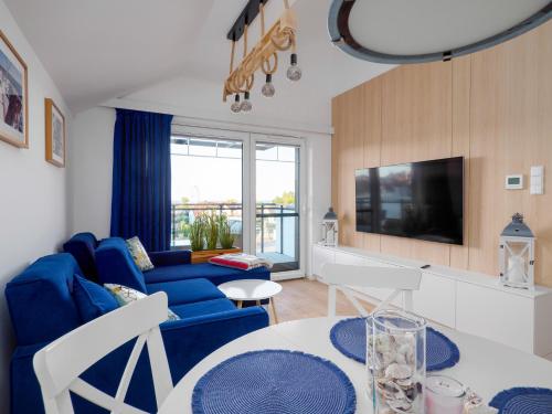 uma sala de estar com um sofá azul e uma televisão em PORT KRYNICA Apartamenty em Krynica Morska