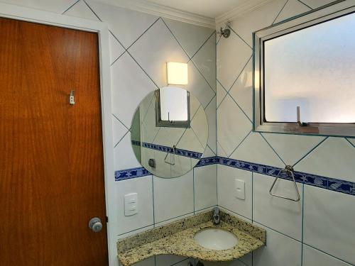 een badkamer met een wastafel en een spiegel bij Flats Enseada Delphin in Guarujá