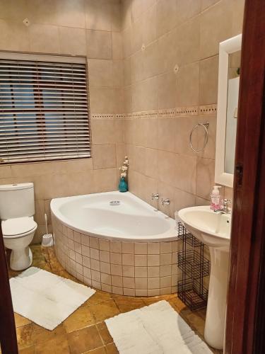 a bathroom with a tub and a toilet and a sink at Fancy Pansy 4: Secure Modern 2 bed family home in Germiston