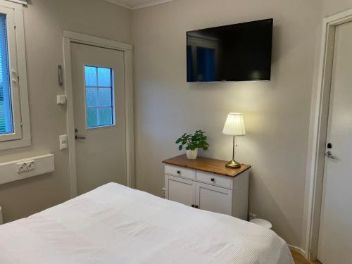 a bedroom with a white bed and a television on the wall at Puuppola Kotikoivu 