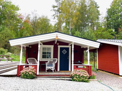 czerwony domek z niebieskimi drzwiami i krzesłami w obiekcie Höga Backe Gästhus w mieście Asphyttan