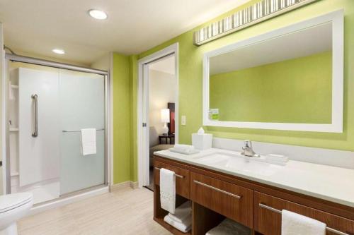 a bathroom with a sink and a toilet and a mirror at Home2 Suites by Hilton Farmington/Bloomfield in Farmington