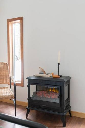 a black fireplace in a living room with a chair at The Doma Lodge - Cozy Muskoka Cabin in the Woods in Huntsville