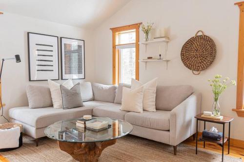 a living room with a couch and a glass table at The Doma Lodge - Cozy Muskoka Cabin in the Woods in Huntsville