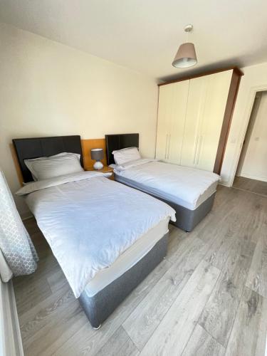 two beds in a room with white sheets at Greeg Court in Dublin