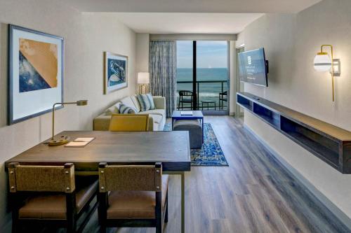 a living room with a table and a couch and a television at Embassy Suites By Hilton Virginia Beach Oceanfront Resort in Virginia Beach
