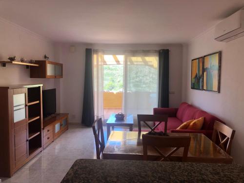 ein Wohnzimmer mit einem roten Sofa und einem Tisch in der Unterkunft Paraíso in Cumbre del Sol