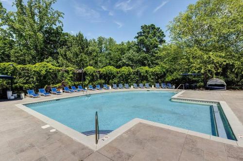 a large swimming pool with lounge chairs and trees at Lake Norman Royal Retreat in Mooresville