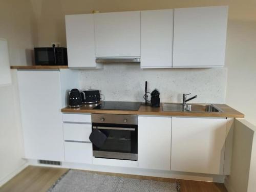 a kitchen with white cabinets and a sink at Au pied du mur in Huy