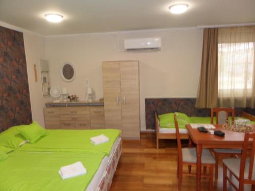 1 dormitorio con cama verde, mesa y cocina en Karneol Apartmanház Cserkeszőlő en Cserkeszőlő